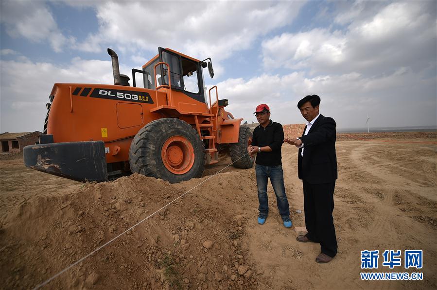 在寧夏鹽池縣曾記畔村，朱玉國（右）在工地查看村飼料加工廠的建設情況（10月20日攝）。新華社記者 李然 攝