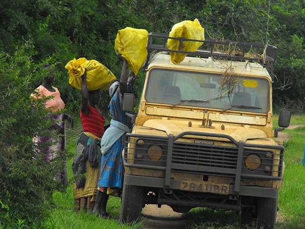 Women who are central suppliers in the bushmeat trade loading their bushmeat packed in Yellow and White sacks on to a tourist vehicle in Murchison Falls National Park. (Photo/Timothy Sibasi)