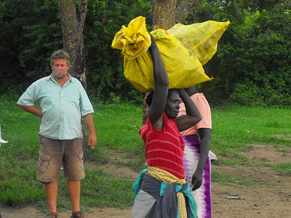 Tourist looks on as women suppliers walk in front of him carrying packed bushmeat in yellow sacks. (Photo/Timothy Sibasi)