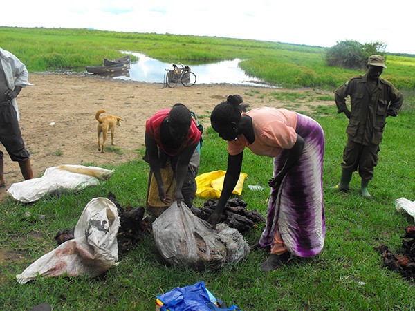 Compromised pack ranger looks on as women suppliers of bushmeat offload for sale, on the right is a hunter. (Photo/Timothy Sibasi)