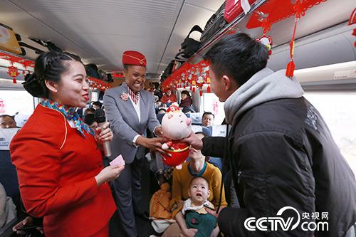 D1979次列車上，“洋班組”留學生為旅客贈送豬年吉祥物。（王曙天 攝）