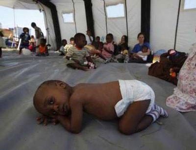 A Haitian orphan huddles on the ground of a tent set up by the Dutch Urban Search and Rescue team at the UN compound located in Port-au-Prince January 20, 2010.REUTERS/Wolfgang Rattay