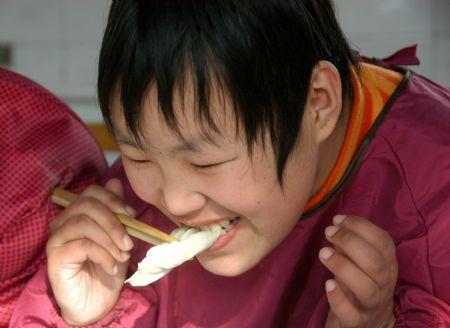 A student tastes a dumpling made by herself at Xingtai Special Education School in Xingtai of north China's Hebei Province, Dec. 22, 2009. 2009. The Winter Solstice Festival, a traditional day for eating dumplings in China, arrived on Tuesday. Volunteers of Xingtai Charity Association came to the school and made dumplings with the students there.(Xinhua/Huang Tao)