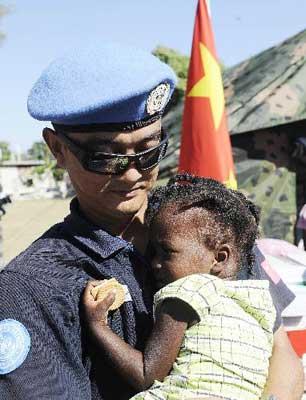 A member of the Chinese anti-riot police team in Haiti holds an orphan in his arms at the orphanage "solidarity and fraternity" in Port-au-Princes, capital of Haiti, Jan. 30, 2010. The Chinese anti-riot police team in Haiti on Saturday donated relief materials to 40 orphans here to help them tide over the difficulties after the recent earthquake. (Xinhua/Wu Xiaoling)