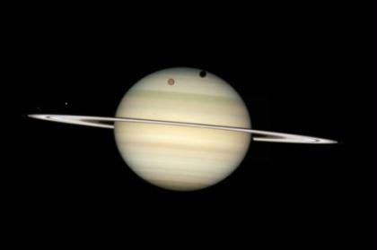 An image of four moons of Saturn passing in front of their parent planet in seen this image taken by NASA's Hubble Space Telescope February 24, 2009 and released by NASA March 17, 2009. In this view, the giant orange moon Titan casts a large shadow onto Saturn's north polar hood. Below Titan, near the ring plane and to the left, is the moon Mimas, casting a much smaller shadow onto Saturn's equatorial cloud tops. Farther to the left, and off Saturn's disk, are the bright moons Dione and the fainter Enceladus. (Xinhua/Reuters File Photo)