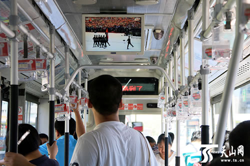 10時56分，烏魯木齊市公交車1號線上，移動電視正在直播“9•3”大閱兵，一位市民就要下車了，視線還停留在電視上。