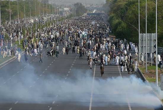 Supporters of executed Islamist Mumtaz Qadri walk through tear gas fired by police during anti-government protest in Islamabad on March 27, 2016.