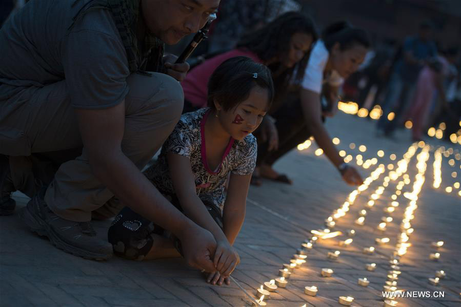 People light up candles to commemorate the people who died in the earthquake a year ago, at Durbar Square in Kathmandu, capital of Nepal, on April 24, 2016. [Photo: Xinhua/Cheong Kam Ka]