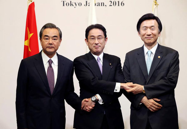 Japanese Foreign Minister Fumio Kishida (C), Chinese Foreign Minister Wang Yi (L) and South Korean Foreign Minister Yun Byung-Se pose for the photographers prior to the official banquet of the trilateral foreign minister