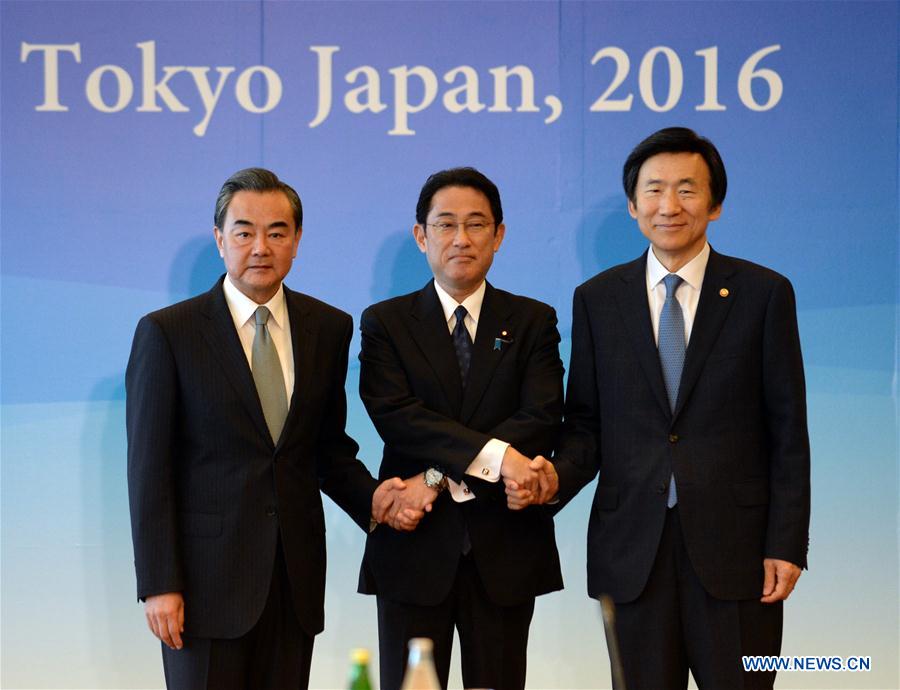 Chinese Foreign Minister Wang Yi, Japanese Foreign Minister Fumio Kishida and South Korean Foreign Minister Yun Byung Se (from L to R) shake hands as they attend the 8th trilateral foreign ministers