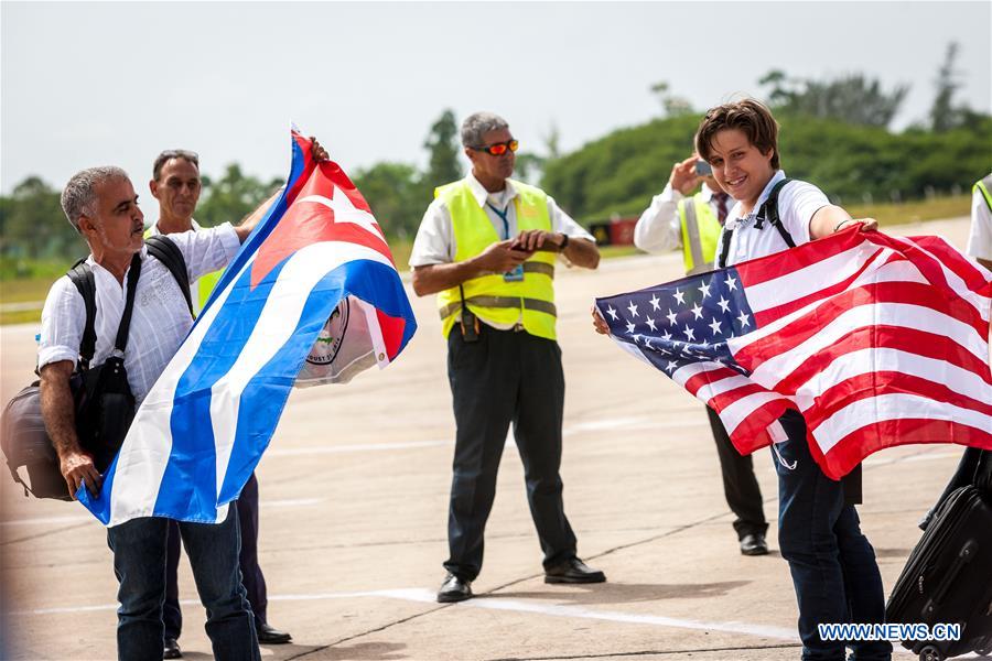 Passengers from the first commercial flight from U.S., pose for pictures with national flags of Cuba and the U.S., at the Abel Santamaria International Airport in the central Cuban city of Santa Clara, Aug. 31, 2016. The first regular direct commercial flight from the United States arrived in the central Cuban city of Santa Clara on Wednesday morning, marking an important new step in thawing ties between the former Cold War foes. (Xinhua/Liu Bin)