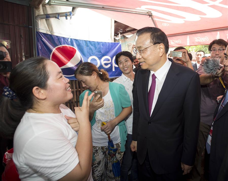 Chinese Premier Li Keqiang (R, front) talks to a woman as he walks into a local shop in Vientiane, Laos, Sept. 9, 2016.(Xinhua/Wang Ye)