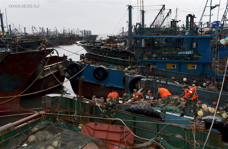 Soldiers help fishermen strengthen fishing boats at a port in Shishi, southeast China