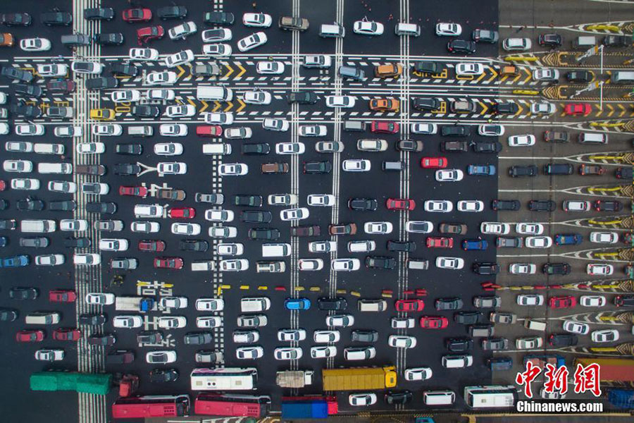 In this aerial view, masses of vehicles queue up to pass through a toll station on an expressway during the National Day holiday travel rush in Nanjing city, East China