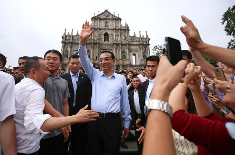 Li Keqiang waves hands to local residents and tourists in front of the ruins of St. Paul, the city