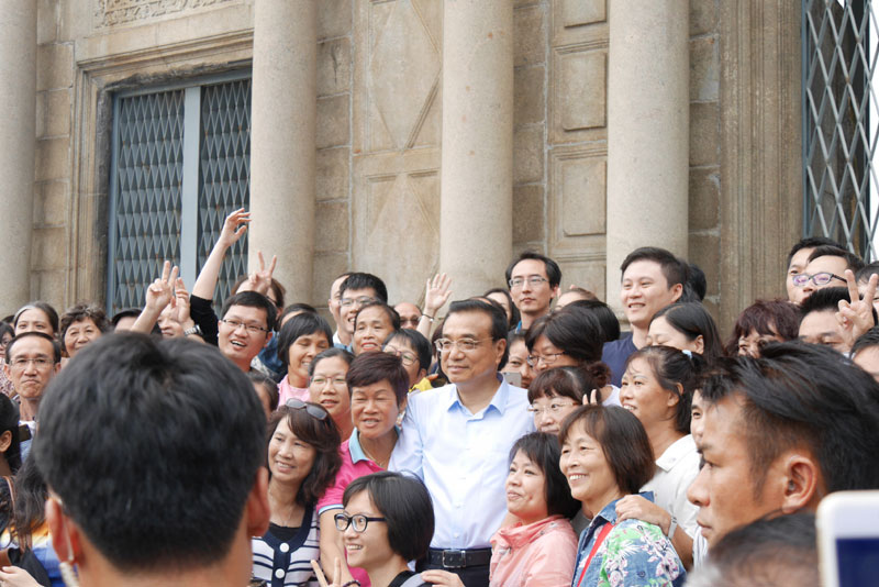 Li Keqiang poses for photos with local residents and tourists in front of the ruins of St. Paul, the city