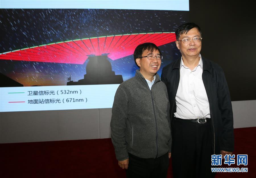 Pan Jianwei (L), the leading scientist in China’s Quantum Science Satellite project, poses with Wang Jianyu, the deputy director of the project, in front of an image showing the transmissions between Quantum Science Satellite Mozi and a ground station during a press conference in Beijing, Oct. 12, 2016. It