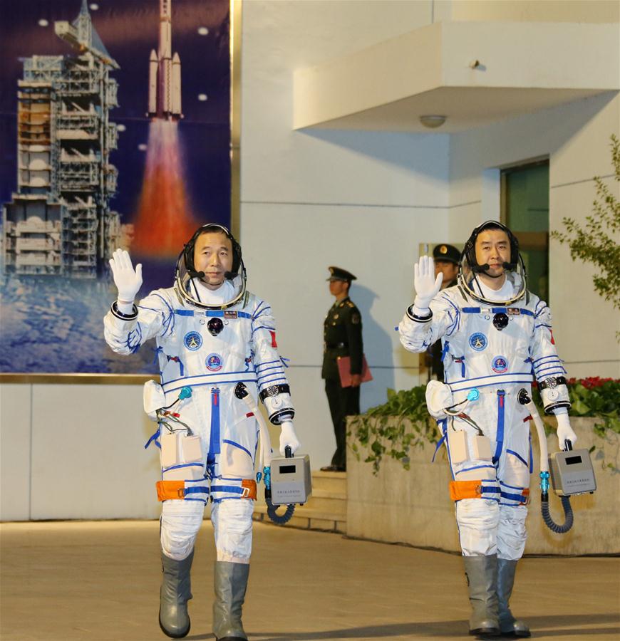 Taikonauts Jing Haipeng (L) and Chen Dong wave during the see-off ceremony of the Shenzhou-11 manned space mission at the Jiuquan Satellite Launch Center in Jiuquan, northwest China