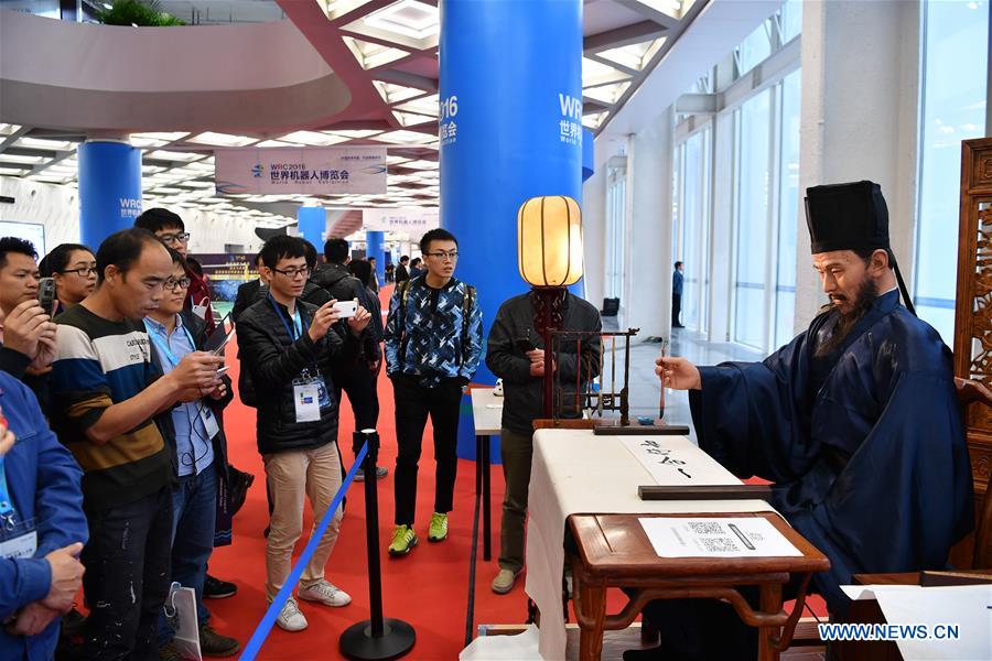 Visitors watch a robot writing calligraphy during the 2016 World Robot Conference in Beijing, capital of China, Oct. 20, 2016. The 2016 World Robot Conference held an opening ceremony here on Thursday, in which about 150 world-famous robot companies took part. (Xinhua/Li Xin) 