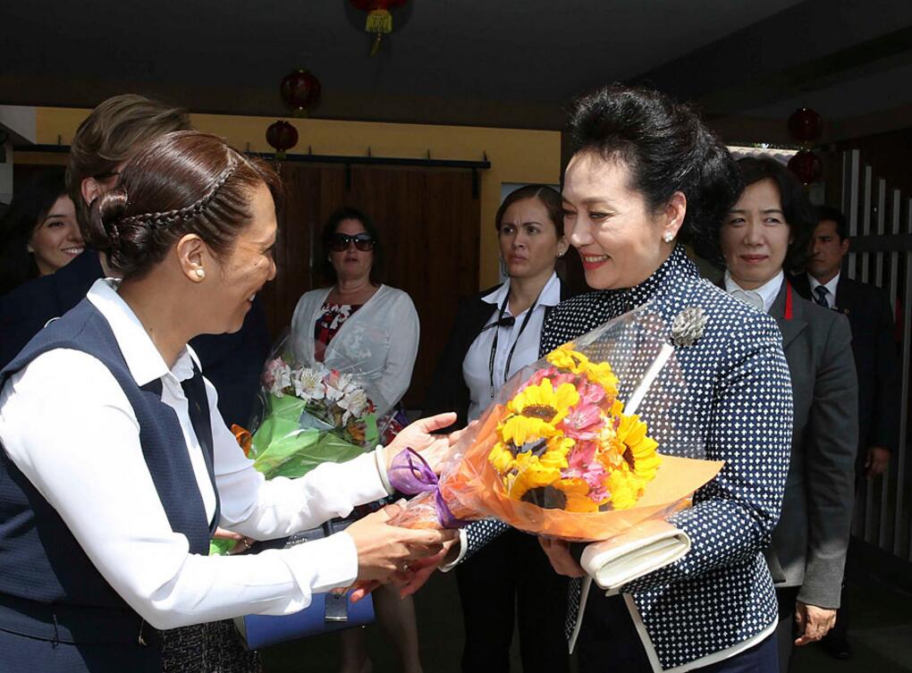 Headmaster of Colegio Peruano Chino Juan XXIII school presents a bouquet to first lady Peng Liyuan. Founded in 1962, the school has students from kindergarten to high school, and remains one of the most famous Chinese-language schools in Peru and Latin America. [Photo/Xinhua]  