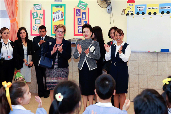 First lady Peng Liyuan applauds as kindergarten children sing Chinese songs "Good mother" and "Birthday song". Peng encouraged the students to learn the Chinese language well and welcomed them to China. [Photo/Xinhua]  