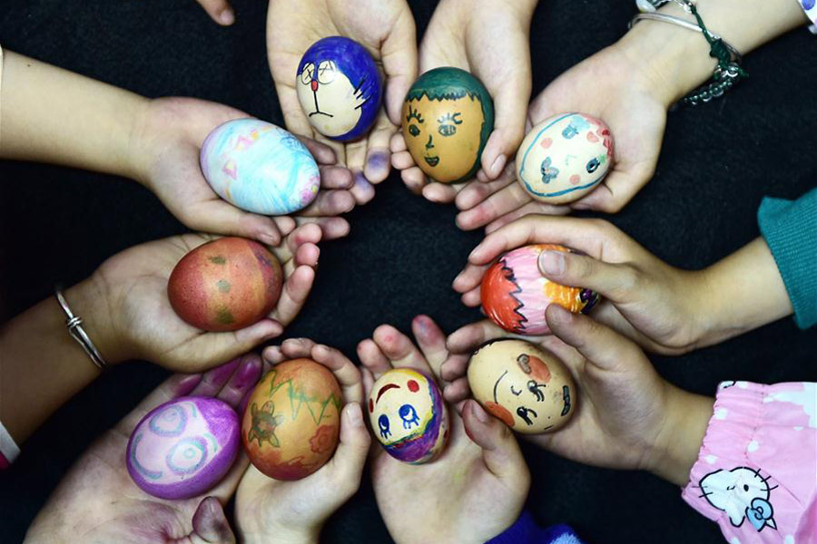 Pupils display painted eggs during a folk custom activity marking "lixia", the beginning of summer in Chinese lunar calendar, at a primary school in Hefei, capital of East China