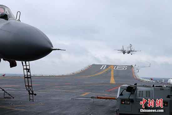 The "Flying Shark" jet fighter takes off from the deck on a signal given by a crew member. Refueling in the sky and air-defense confrontation were also part of the training exercise. [Photo: chinanews.com]