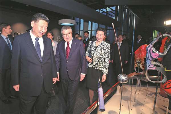 President Xi Jinping and IOC President Thomas Bach look at the badminton racket of former world champion Li Lingwei (right) at the Olympic Museum in Lausanne on Wednesday. Li is now vice-president of the Chinese Olympic Committee. [Photo by Yao Dawei/Xinhua]