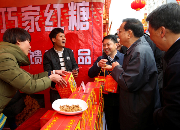 Premier Li bought several boxes of cane sugar after a short walk around the more than 20 stalls in an unexpected visit to the street on the morning of Jan 23.