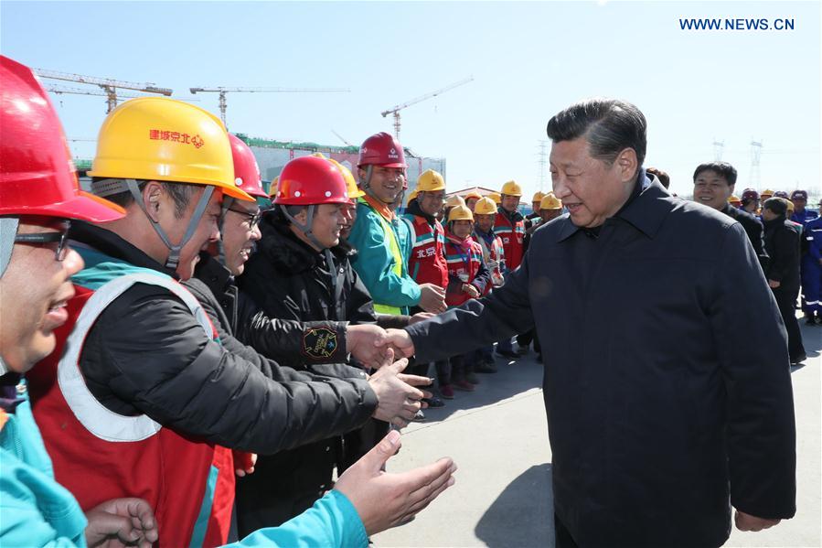 Chinese President Xi Jinping (R, front) shakes hands with workers at the construction site of the capital