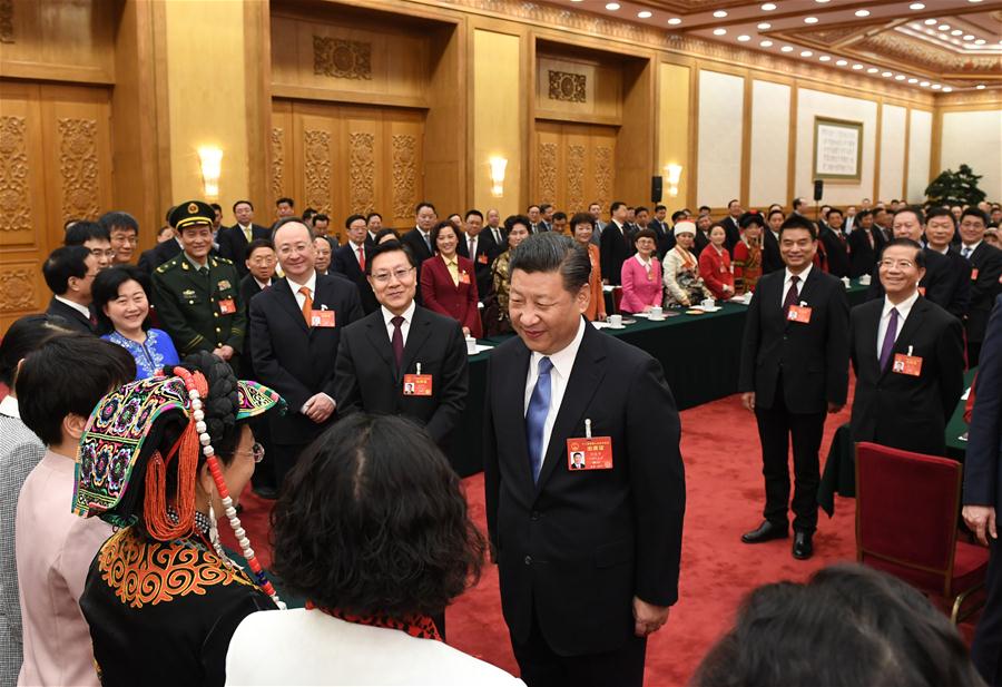 Chinese President Xi Jinping talks with female deputies when joining a panel discussion with deputies to the 12th National People