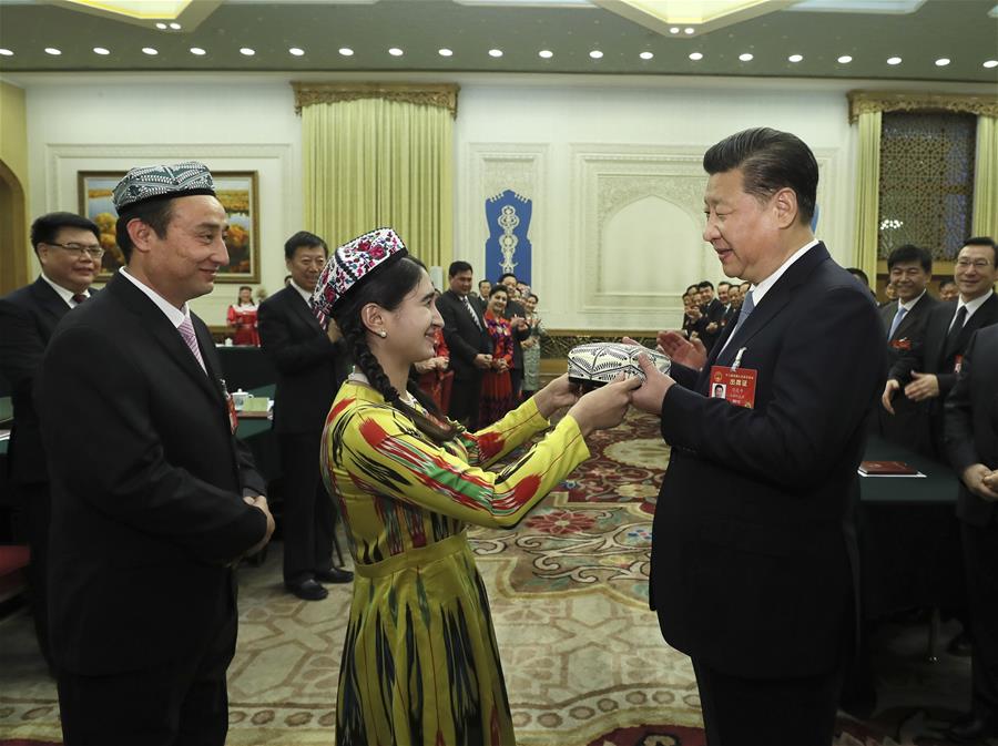 Chinese President Xi Jinping receives a traditional Uygur hat, a gift symbolizing the highest respect and best wishes from people of all ethnic groups in Xinjiang, when joining a panel discussion with deputies to the 12th National People