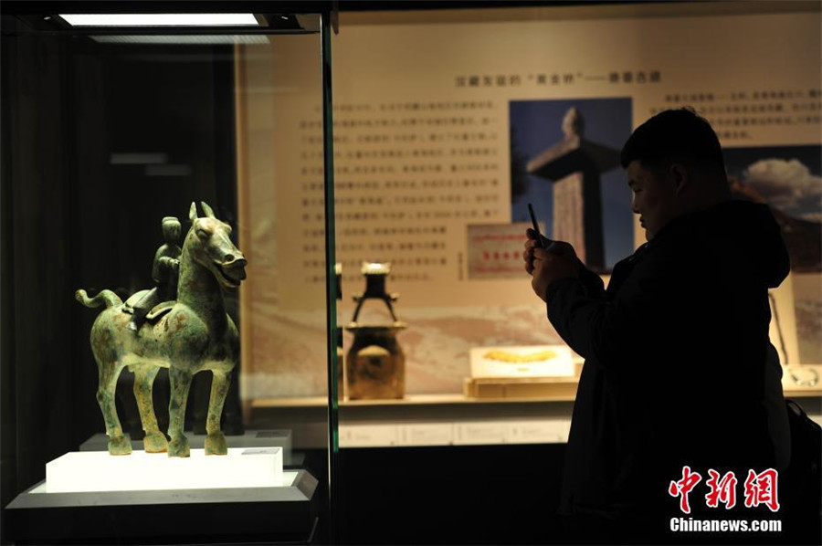 A visitor takes picture of a bronze figurine of a man riding a horse at the exhibition of antiques collected from the Ancient Tea Horse Route at Liaoning Provincial Museum in Shenyang, capital of Northeast China