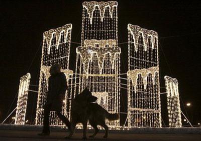 A Warsaw resident walk her dog in front of Christmas lights in the capital city Warsaw, Poland, on Saturday, Dec. 5, 2009.(AP Photo/Czarek Sokolowski)