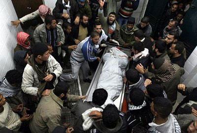 Palestinians mourn over the body of one out of three Islamic Jihad militants killed in an Israeli air raid, at the morgue of Al-Aqsa hospital in Deir Al-Balah refugee camp in the central Gaza Strip. (AFP/Mahmud Hams)