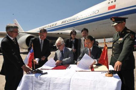 Chinese Ambassador to Chile Lu Fan (2nd R) and a Chilian official (3rd R) sign on the documents about the aid goods at the airport in Santiago, capital of Chile, March 5, 2010. A Chinese plane carrying 2 million U.S. dollars worth of aid goods arrived