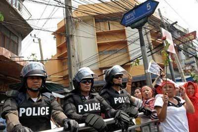 Thai police stand guard as anti-government protesters parade through the streets of Bangkok. Politically riven Thailand was in a stalemate Saturday as protesters, buoyed by a huge parade across the capital, refused talks with the government announced earlier by the prime minister. (AFP/Christophe Archambault)