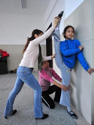 Deaf-mute student Liu Yidan (R) stretches her leg with the assistance of a classmate and her teacher Feng Yan (L) during a dance class at a special education school in Yichang City, Central China錛噑 Hubei province, November.