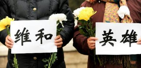 Mourners holding banners wait for the arrival of the coffins of the eight peacekeeping police officers who were killed in the Haiti earthquake at the Babaoshan Revolutionary Cemetery in Beijing Jan. 19, 2010. The coffins of the eight peacekeeping police officers are to be brought here on Tuesday. (Xinhua/Wang Jianhua)