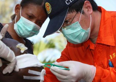 A medic of China International Search and Rescue Team (CISAR) redresses the wound for an earthquake survivor in Port-au-Prince, Haiti, on Jan. 17, 2010. Members of CISAR continue to offer medical services in Haiti. (Xinhua Photo)