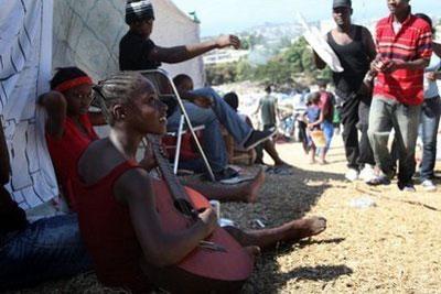 A young Haitian girl plays a guitar at a temporary camp for more than 25,000 people who lost their houses in the devastating earthquake. (AFP/Julien Tack)