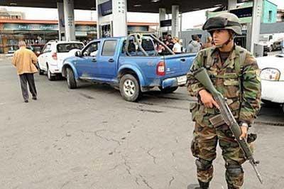 A Chilean soldier in combat gear stands guard at a petrol station in Concepcion, Chile. (AFP/Evaristo Sa)