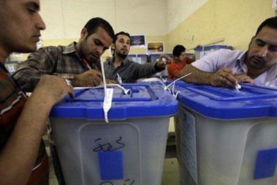 Iraqi employees of the electoral counting and sorting center register more votes in Baghdad. (AFP/Ali al-Saadi)