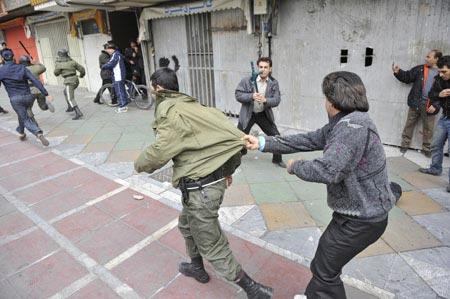 An Iranian opposition supporter holds a policeman during clashes in central Tehran December 27, 2009.(Xinhua/Reuters Photo)