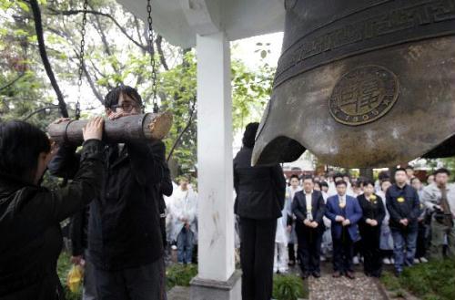 Students of Fudan University ring a bell to pay respect to the victims of Yushu earthquake during a mourning ceremony in Shanghai, east China, April 21, 2010. (Xinhua/Liu Ying)