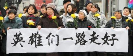 Mourners holding a banner wait for the arrival of the coffins of the eight peacekeeping police officers who were killed in the Haiti earthquake at the Babaoshan Revolutionary Cemetery in Beijing Jan. 19, 2010. The coffins of the eight peacekeeping police officers are to be brought here on Tuesday. (Xinhua/Wang Jianhua)