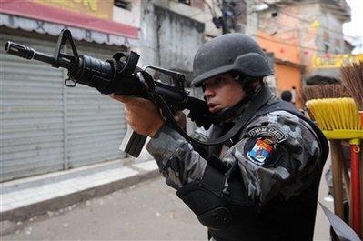 A police officer aims a weapon during an operation at the Jacarezinho slum in Rio de Janeiro, Monday, Oct. 19, 2009. Police in Rio de Janeiro say they found two more bodies in a slum wracked by violence just two weeks after the city won the 2016 Olympic games.(AP Photo/Felipe Dana) 