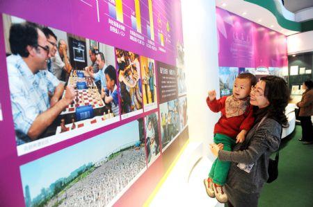 A woman holding her baby visits an exhibition of the achievements of the Macao Special Administrative Region (SAR) over the past decade, at the Capital Museum in Beijing, Dec. 12, 2009. The exhibition opened to the public from Saturday. (Xinhua) 