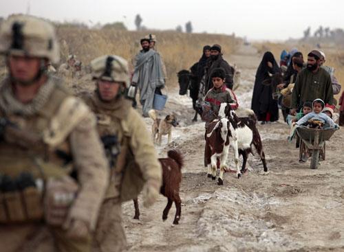 Afghans walks behind U.S. Marines from Bravo Company of the 1st Battalion, 6th Marines during an operation in Marjah, Helmand province February 21, 2010. NATO forces are facing strong resistance eight days into a major offensive in southern Afghanistan as Taliban fighters dig in to fight to the death.(Xinhua/Reuters Photo)