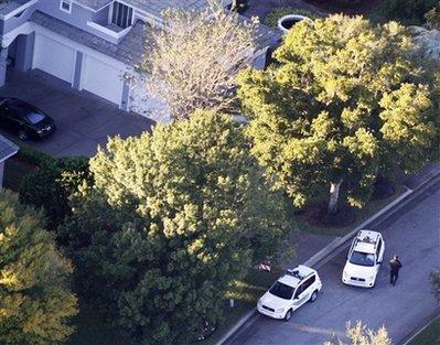 Security guards gather near Tiger Woods' home, left, in Windemere, Fla., Friday, Nov. 27, 2009. Woods sustained facial cuts in a minor car accident early Friday when his SUV hit a fire hydrant and a neighbor's tree as he was leaving his mansion in a gated waterfront community near Orlando, Fla. (AP Photo/Gourav Mukherjee)
